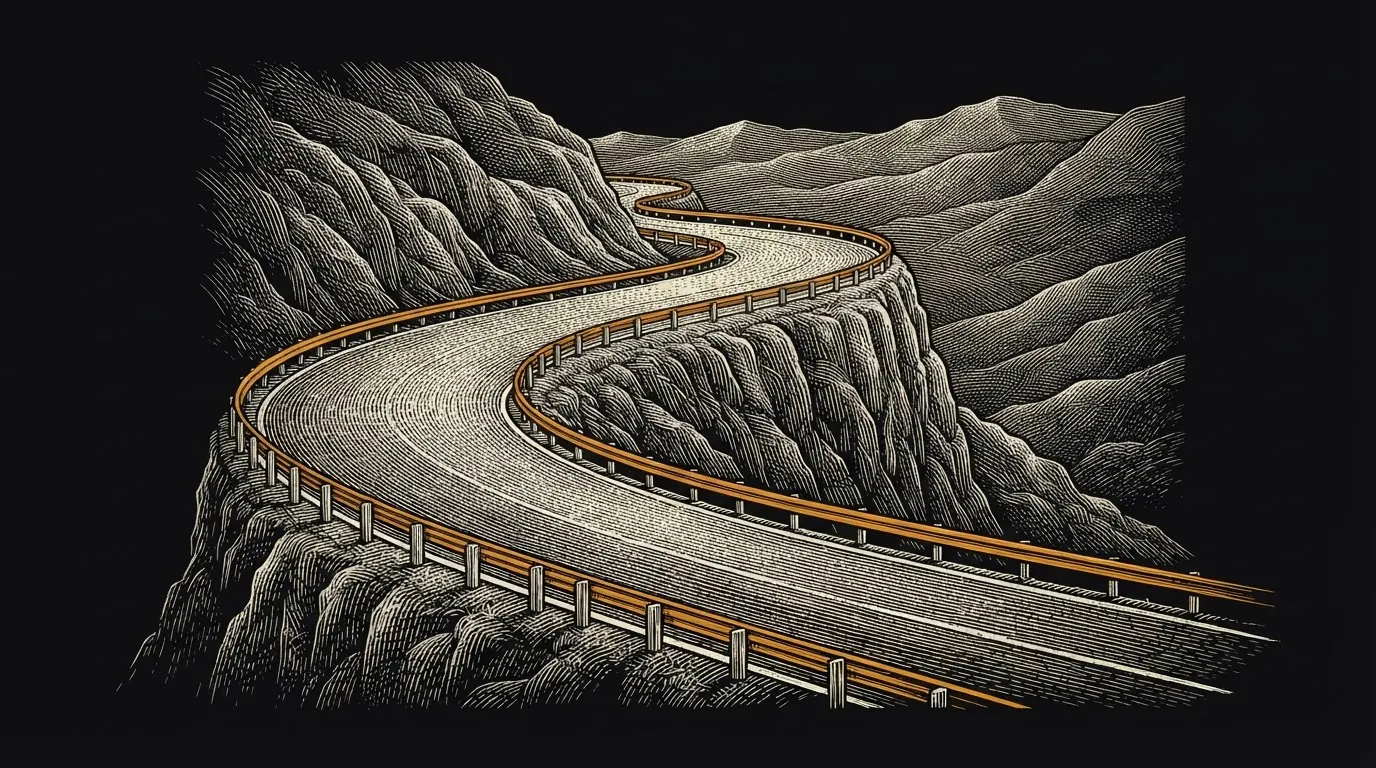 A winding cliffside road lined with orange guardrails on both edges.